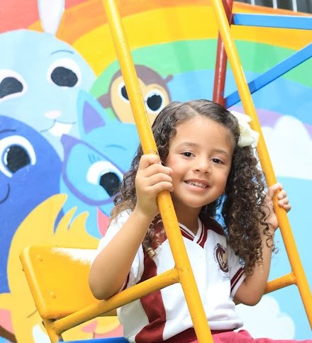 Aluna da Educação Infantil sorrindo no balanço do parquinho