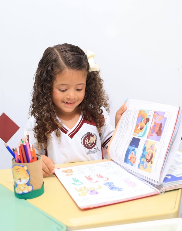 Aluna do CEC sorrindo com o livro aberto na aula de Inglês