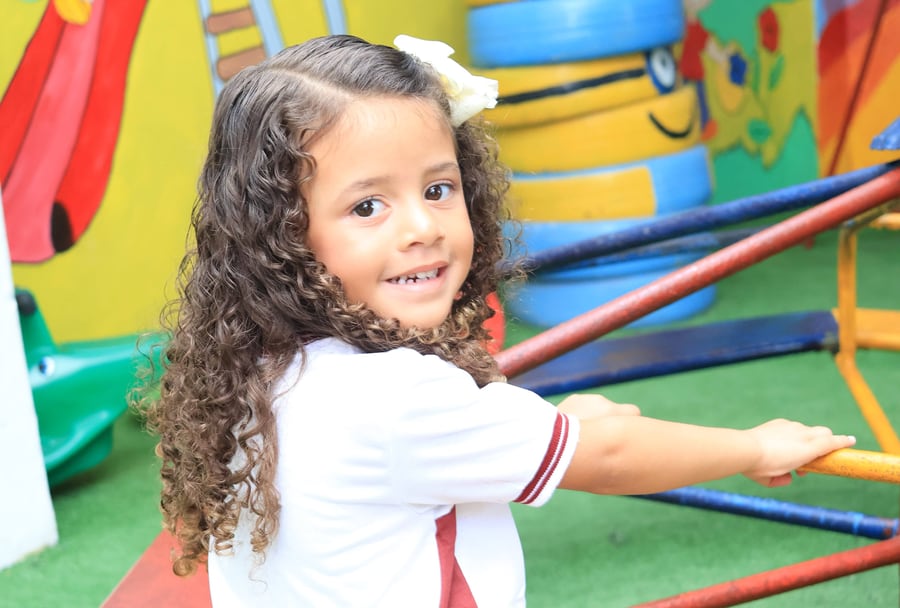 Aluna do CEC sorrindo na gangorra do parquinho